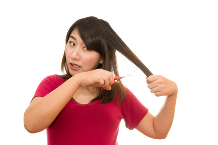 woman cutting her hair with scissors - unhappy expression, isolated on white backgroundの写真素材