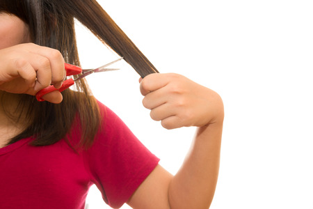 woman cutting her hair with scissors - unhappy expression, isolated on white backgroundの写真素材