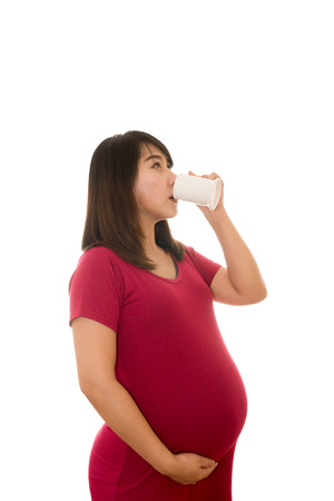 Portrait of pregnant woman with milk in glass isolated on whiteの写真素材