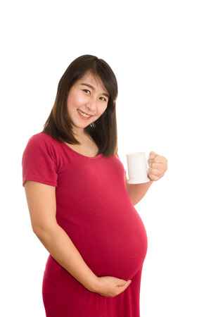 Portrait of pregnant woman with milk in glass isolated on whiteの写真素材
