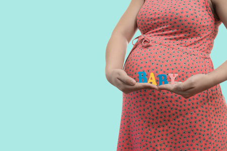 Label "Baby" in the hands of a pregnant woman on blue background soft colorの写真素材
