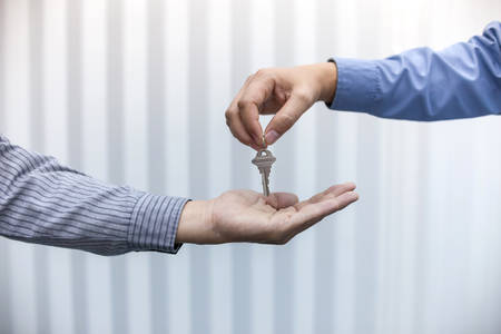 Estate agent giving house keys to man in officeの写真素材