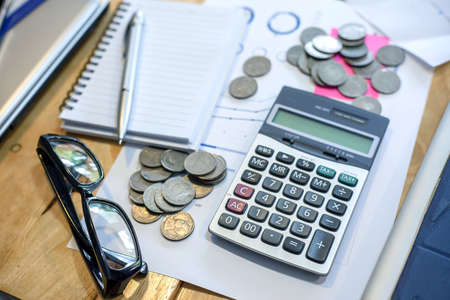 Calculator, notebook, pen, coins on his desk. To calculate incomeの写真素材