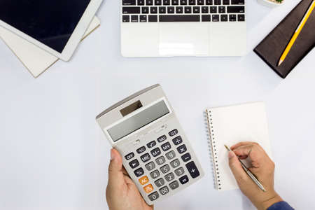 Top view. Man using calculator and writing make note with calculate in the office and Monitoring...