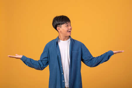 Happy smiling young Asian man Ready to open arms when receiving friendly Positive greetings. On orange backgroundの写真素材