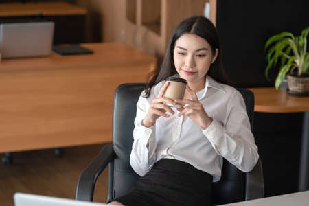 Asian businesswoman happy relaxing and drinking coffee at the office.の写真素材