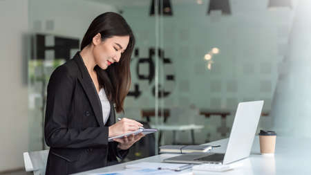 Side view of Asian businesswoman taking notes at the office.の写真素材