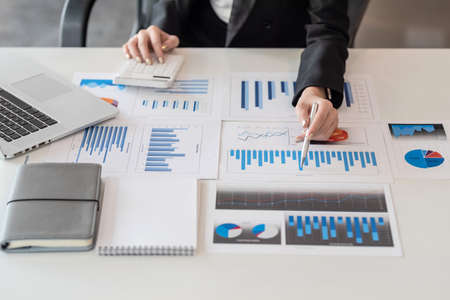 Close up of a businesswoman pointing to a graph with a calculator at the office.