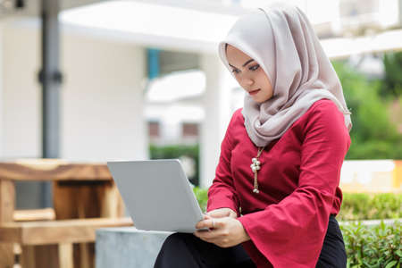 Young asian muslim woman working on laptop outdoorの写真素材