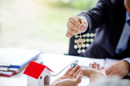 Real estate agent giving keys to couple of customers. Trading house for rent and insurance