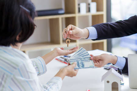 Real estate agent giving keys to couple of customers. Trading house for rent and insuranceの写真素材