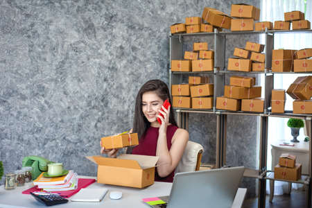 Selling products online. Portrait of a pretty woman phone talking to clients for shipping.の写真素材