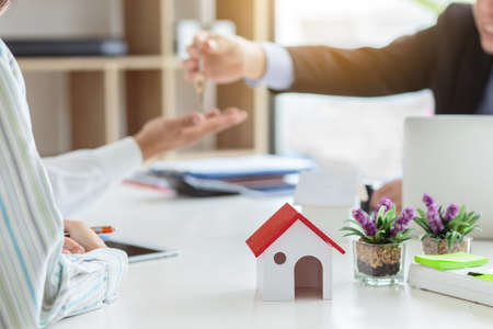 Real estate agent giving keys to couple of customers. Trading house for rent and insuranceの写真素材