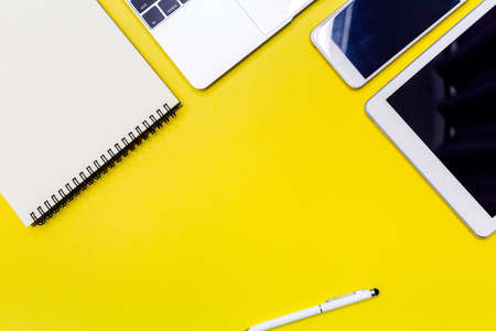 Yellow office desk table with  blank notebook, tablet, calculator and other office supplies. Top...