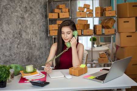 Selling products online. Portrait of a pretty woman phone talking to clients for shipping. Pack and delivery to the customer.の写真素材