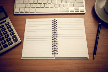 Notebook is on the table with calculator and coffee and computer keyboard. Vintage styleの写真素材