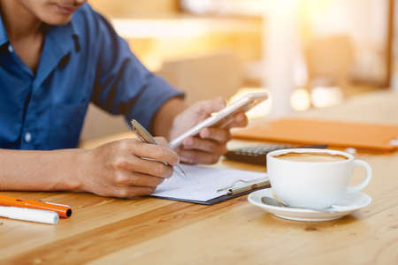 Man hand taking notes information and searching for in the mobile smartphoneの写真素材