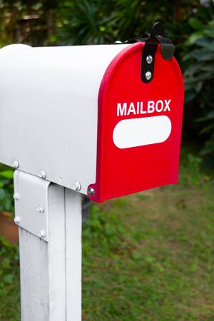 Red and white mail box in green gardenの写真素材