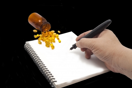 Writing notes or planning a schedule to eat a fish oilの写真素材