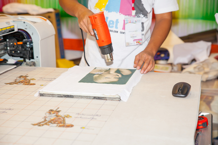 BANGKOK - JUNE 28  Unidentified worker show digital t-shirt printer work with Sewing machine at Garment Manufacturers Sourcing 2014 2014 on June 28,2014 in BITEC ,Bangkok, Thailand のeditorial素材