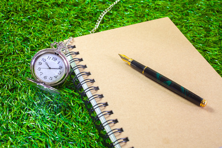 fountain pen and pocketwatch on bookの写真素材