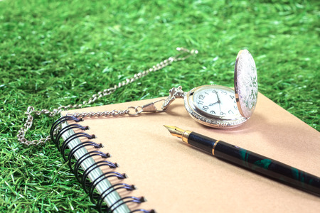 fountain pen and pocketwatch on bookの写真素材