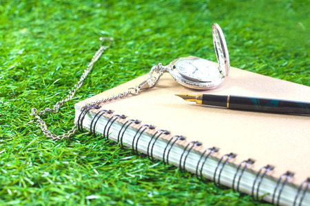 fountain pen and pocketwatch on bookの写真素材