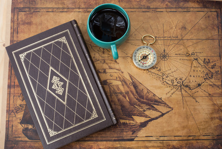 hot coffee cup and compass on old mapの写真素材