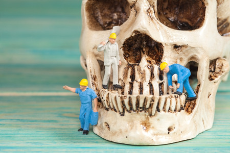 Miniature worker working on old skull,selective focusの写真素材