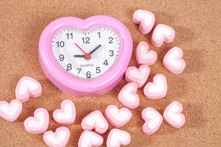 clock and heart shape of marshmallows on wooden.selective focus.の写真素材