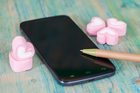 heart shape of marshmallows with smart phone on wood.selective focus.の写真素材