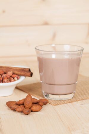 Almonds in  bowl on wooden background and chocolate milkの写真素材