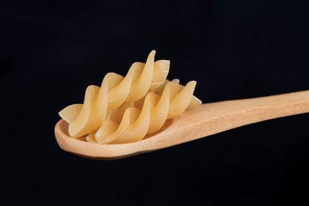 Raw uncooked pasta penne in wood spoonの写真素材