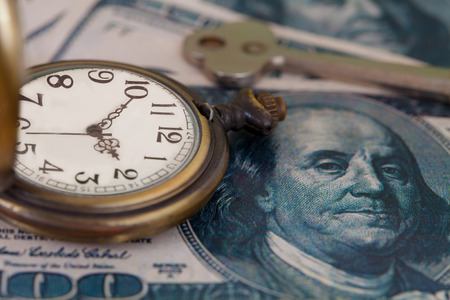 Time and money concept image - old silver pocket watch and US currency .vintage style light and tone