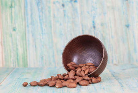 Almonds in brown bowl on textured wooden backgroundの写真素材