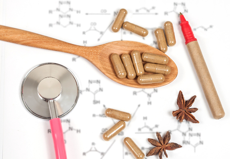 Capsules of herbs on spoon and stethoscopeの写真素材