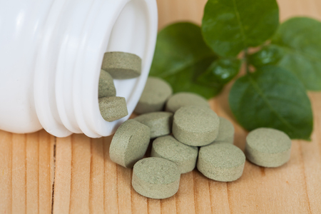 herb pill spilling out of a bottleの写真素材