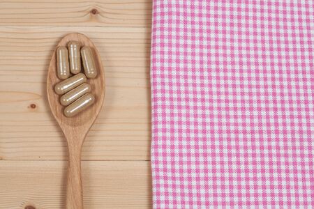 Herbal capsules on wooden spoon. herb for healthy 
living.の写真素材