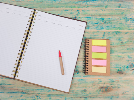 Blank white notebook and pen on wooden table