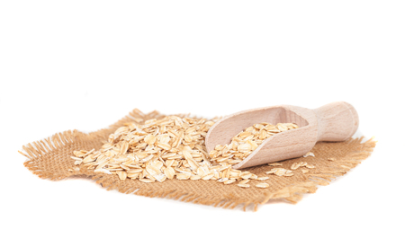 Oats flakes pile in wood spoon on white backgroundの写真素材