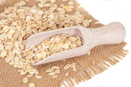 Oats flakes pile in wood spoon on white background