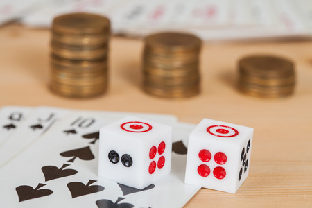Two dices on wood table with coines stack and cardの写真素材