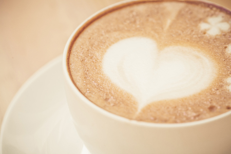 heart symbol on latte coffee cup on table fresh water bottle with paper cup on tableの写真素材