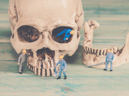 Miniature worker working on old skull,selective focusの写真素材