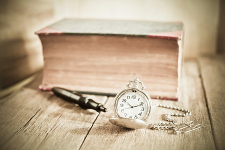 vintage pocket clock and old books on wood tableの写真素材