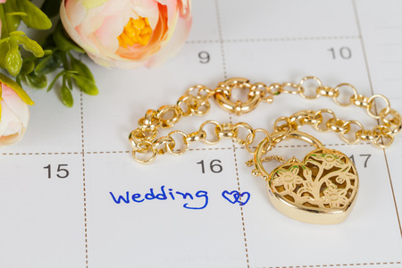 word wedding on calendar and gold bracelet with heartの写真素材