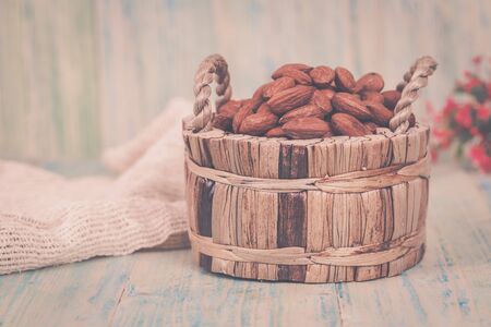 Almonds in brown bowl on textured wooden backgroundの写真素材
