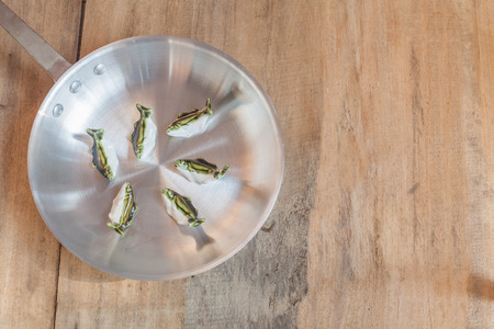 metal pan and small fishs on woodの写真素材