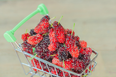 Mulberry in shopping cart on woodの写真素材