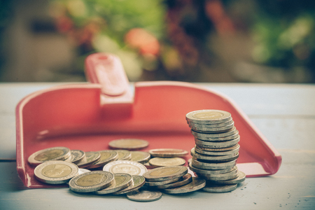 coin or money in dust pan on woodの写真素材